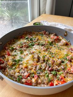 a casserole dish with meat and vegetables in it on a table next to a window