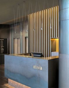 the front desk of an office building with lights hanging from it's ceiling and wood flooring