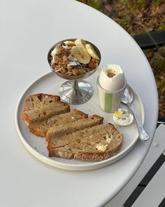 a white plate topped with slices of bread next to a bowl of fruit and yogurt