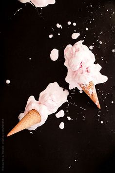 two ice cream cones with sprinkles on a black surface