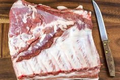 a piece of meat sitting on top of a cutting board next to a knife