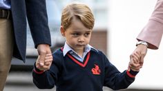 a little boy holding the hand of an adult