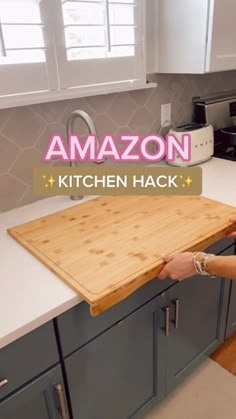 a woman standing in front of a kitchen counter with a cutting board on top of it