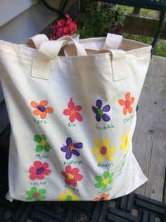 a white bag with colorful flowers on it sitting on a bench next to a potted plant