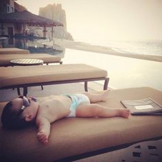 a baby laying on top of a chair next to the ocean