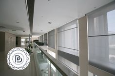 an empty hallway with windows and blinds on the wall, along with a plant in a vase