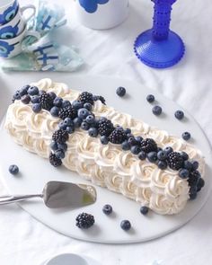 a piece of cake on a plate with blueberries and blackberries around the edges