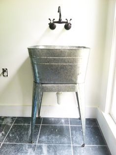 a metal tub sitting on top of a black tile floor