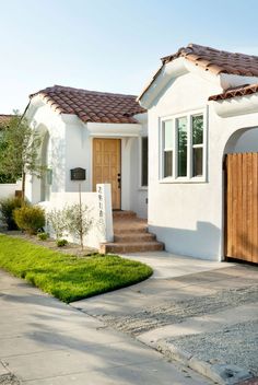 a white house with brown shingles and wooden doors