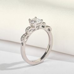 Imagine a slender band wrapping around your finger, with a graceful bow adorning its profile. This exquisite design adds a touch of whimsy and elegance to any ensemble. It's a symbol of grace and sophistication, perfect for those who appreciate understated beauty and charm.Carat Weight: 0.6 ctStone Size: 5.5 mmStone Type: Jeulia® StoneNumber of Stones: 1 Stone Color: Diamond WhiteStone Shape: RoundCarat Weight: 0.33 ctStone Size: 1.2,1.5 mmStone Type: Jeulia® StoneNumber of Stones: 14 Stone Colo Dainty Adjustable Diamond Ring For Formal Occasions, Elegant Silver Infinity Ring, Elegant Formal Diamond Ring With Decorative Band, Elegant Infinity White Gold Rings, Elegant White Gold Infinity Ring, Elegant Adjustable Promise Ring, Diamond Bow Jewelry For Weddings, Elegant Round Band Diamond Ring As A Gift, Elegant White Gold Rings With Decorative Band