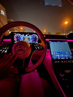 the interior of a car is lit up with pink lights and features electronic devices, including an iphone