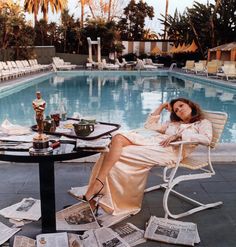 a woman sitting at a table next to a pool