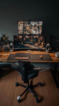 a desk with a keyboard, monitor and speakers on it in front of a dark wall