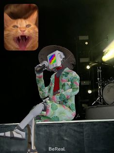 a cat with its mouth open sitting in front of a person wearing a hat and holding a microphone