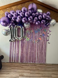 purple balloons and streamers are hanging from the wall