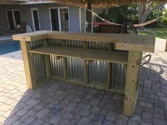 a wooden table sitting next to a pool with a tiki hut on top of it