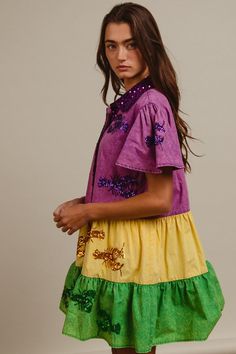 a young woman in a colorful dress poses for the camera with her hand on her hip