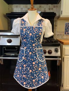 an apron on a mannequin in front of a stove top oven and cabinets