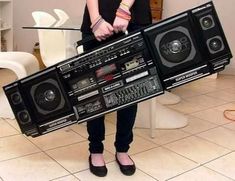 a woman holding two boomboxes in her hands