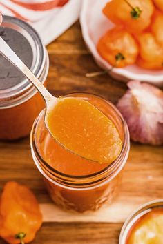 a spoon full of sauce next to some tomatoes and garlic on a cutting board with other foods in the background