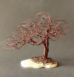 a wire sculpture of a tree on top of a rock with roots growing out of it