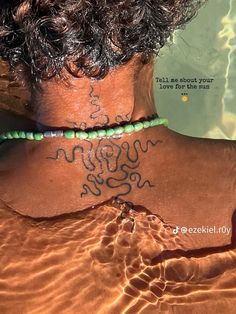 the back of a woman's neck with tattoos and beads on her neck is covered in water