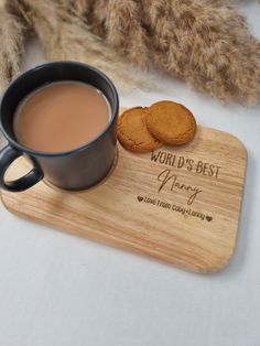 a cup of tea and two cookies on a wooden coaster that says world's best