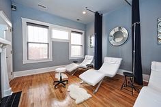 a living room with blue walls and white furniture in the center, along with hardwood flooring