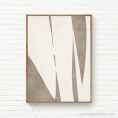 a white brick wall with a brown frame hanging on it's side and an abstract painting in the middle