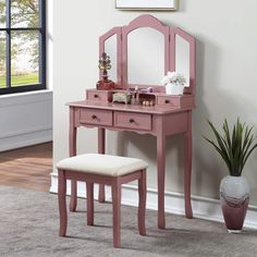 a pink vanity table with mirror and stool in front of a large window on a carpeted floor