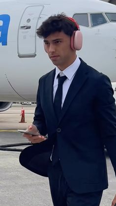 a man wearing headphones is standing in front of an airplane