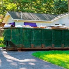 a green dumpster sitting in front of a house