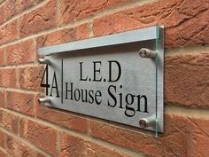 a metal sign mounted to the side of a brick building that reads 4 led house sign