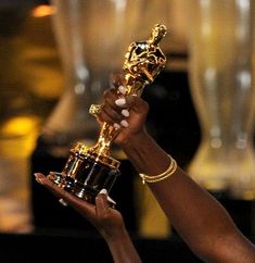 a woman holding up an oscar statue