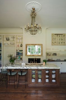 a large kitchen with marble counter tops and wooden flooring in front of a chandelier