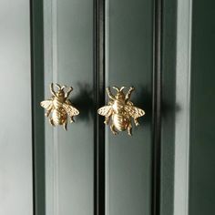 two gold bees are hanging on the side of a green door