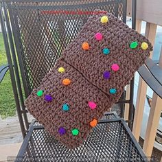 a crocheted pillow sitting on top of a chair with pom - poms