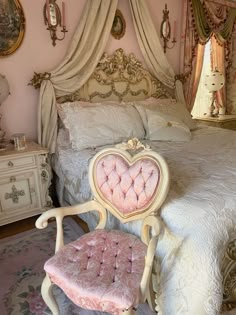 a pink chair sitting next to a white bed in a room with gold trimmings