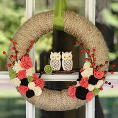 a wreath with two owls sitting on top of it next to a window sill