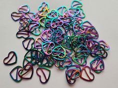 a pile of multicolored paper clips sitting on top of a white table next to each other