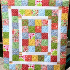 a colorful quilt hanging on the side of a fence