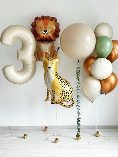 an animal balloon and some balloons in the shape of numbers are on display against a white wall