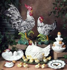 three chickens are standing next to each other in front of some plates and bowls on the ground