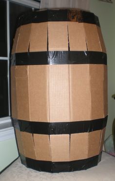 a large cardboard barrel sitting on top of a white table next to a black window