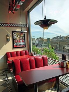 a restaurant with red booths and checkered flooring, looking out onto the street