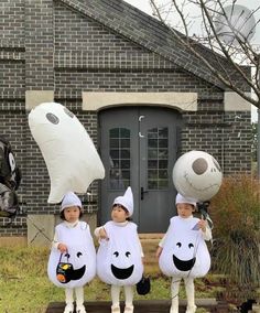 three children dressed up in costumes standing on a platform with balloons attached to their heads