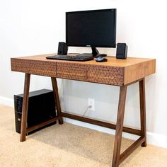 a computer desk with a keyboard and mouse on top of it next to a wall