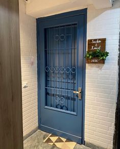 a blue door is in front of a white brick wall with a sign on it