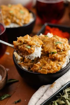 a bowl filled with rice and meat covered in gravy on top of a wooden table