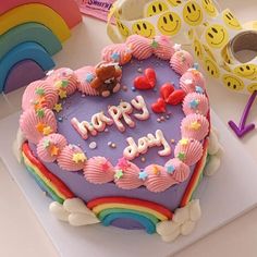 a heart shaped cake with the words happy birthday written on it, surrounded by other decorations